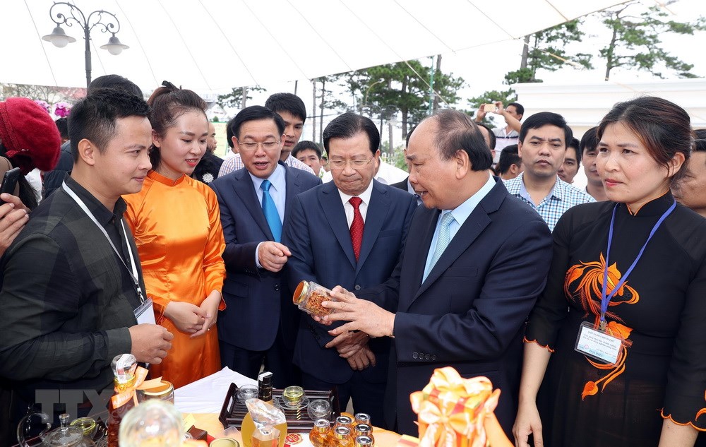 Thủ tướng Nguyễn Xuân Phúc và các Phó Thủ tướng tham quan gian trưng bày sản phẩm tại hội nghị. (Ảnh: Thống Nhất/TTXVN)