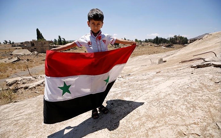 Một đứa trẻ tại Quneitra cầm cờ Syria sau khi khu vực này sạch bóng khủng bố IS.