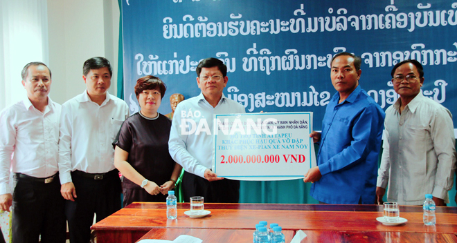 Deputy Secretary Tri (4th, left) presenting 2 billion VND to representatives from the Attapeu Province authorities