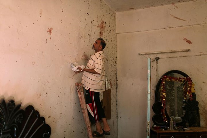 Người đàn ông đang lau sạch các vết máu trên tường trong căn nhà của người phụ nữ và đứa con 18 tháng tuổi đã thiệt mạng.