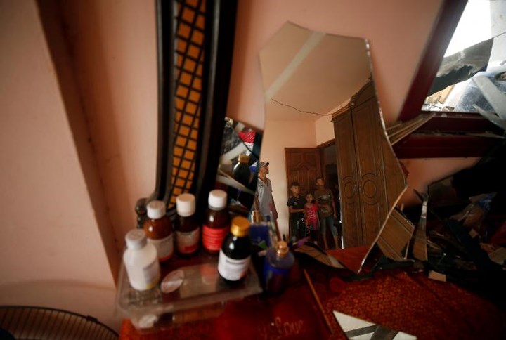 Hình ảnh người dân Palestine phản chiếu qua tấm gương trong căn nhà bị tàn phá vì bom đạn.