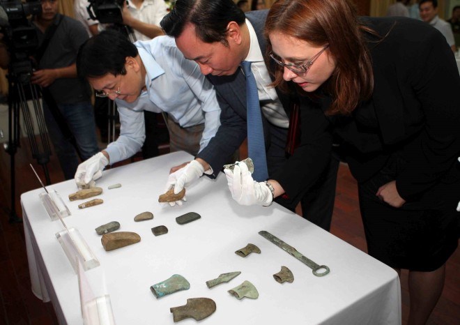 Officials examine the antiques at the hand-over ceremony