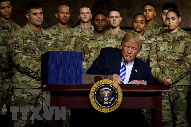 Tổng thống Mỹ Donald Trump (phía trước) ký ban hành Đạo luật Chi tiêu Quốc phòng (NDAA) tài khóa 2019 tại căn cứ Fort Drum ở New York ngày 13/8. (Nguồn: AFP/TTXVN)