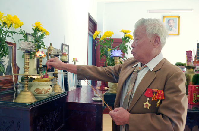 Ông Châu Quang Bút đang thắp hương cho hai người anh Liệt sĩ tại bàn thờ tổ tiên. 