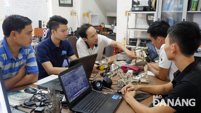 Anh Trần Ngọc Việt (ngoài cùng bên trái) và anh Phan Chánh Hiền (thứ 3 từ trái) cùng các thành viên trong dự án STEMbot thảo luận về ý tưởng cho sản phẩm mới.  Ảnh: Mai Hiền