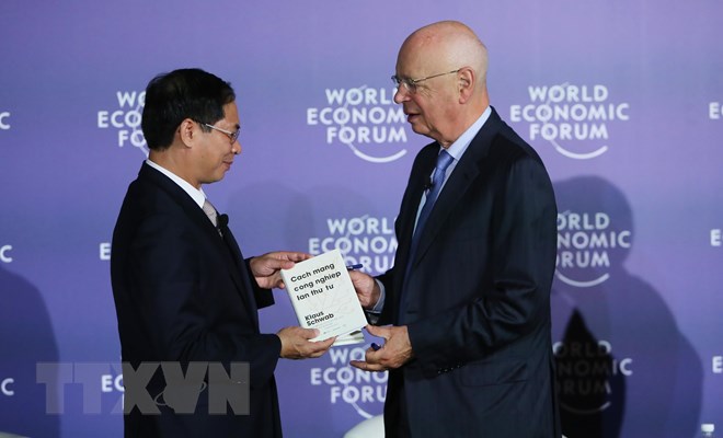 Giáo sư Klaus Schwab, Người sáng lập, Chủ tịch Điều hành Diễn đàn Kinh tế thế giới (bên phải) trao sách tặng Thứ trưởng Thường trực Bộ Ngoại giao Bùi Thanh Sơn. (Ảnh: Lâm Khánh/TTXVN)