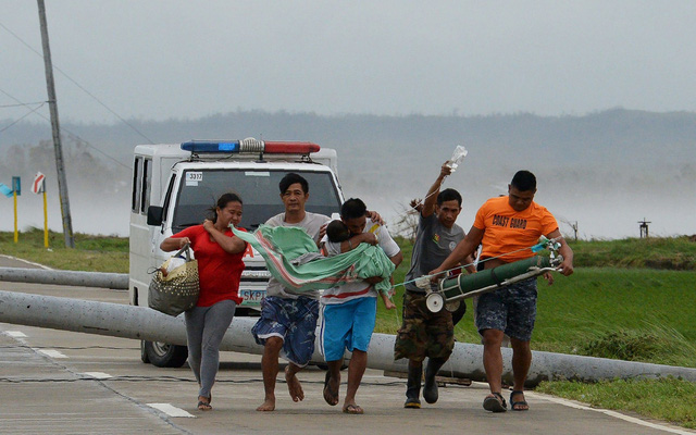 Bão Mangkhut đã phá hủy một sân bay và nhiều đoạn đường đóng vai trò quan trọng trong việc vận chuyển hàng cứu trợ tại Philippines. Trong ảnh: Một người cha ôm con trai bị ốm từ xe cấp cứu sang một xe khác sau khi xe cấp cứu bị cột điện đổ chắn ngang đường do gió lớn tại tỉnh Cagayan. (Ảnh: AFP)