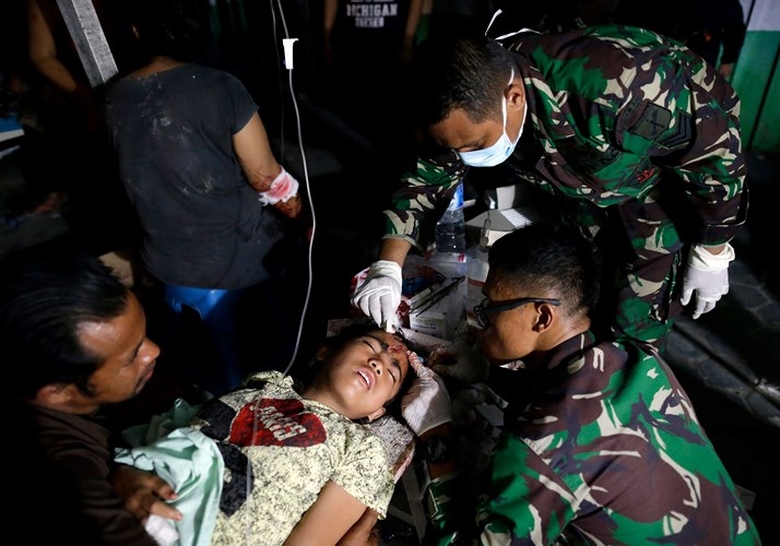 Một người còn sống sau vụ động đất, sóng thần ở Indonesia được đưa tới chăm sóc y tế bên ngoài một bệnh viện quân đội ở Palu. Ảnh: EPA 