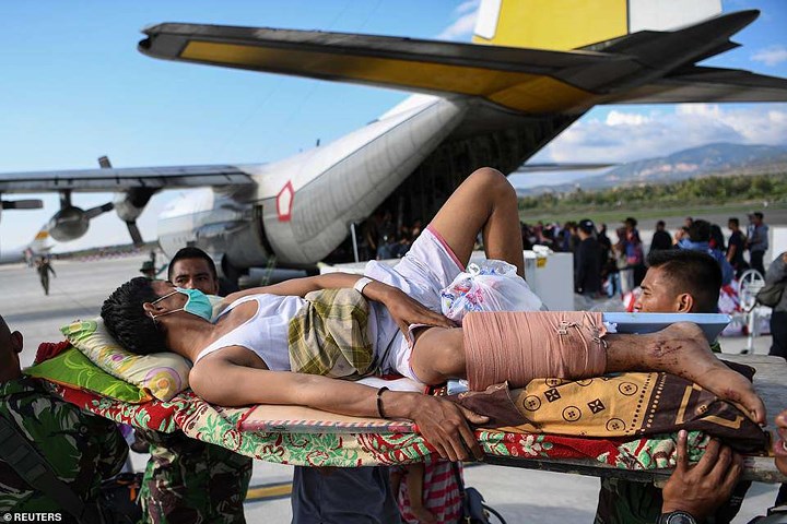 Một người đàn ông bị thương được đưa đi cấp cứu trên một chiếc máy bay quân đội sau khi thảm họa thiên nhiên xảy ra ở Palu. Ảnh: Reuters 