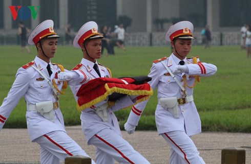 Tại Quảng trường Ba Đình, các sĩ quan thuộc Bộ Tư lệnh Bảo vệ Lăng Chủ tịch Hồ Chí Minh mang theo dải băng tang để buộc vào lá cờ Tổ quốc.