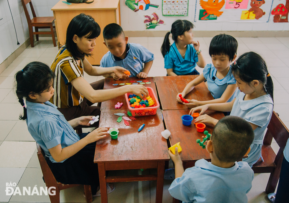 Cô Nguyễn Thị Thu Thảo, giáo viên tại cơ sở 1 hướng dẫn các em học sinh chơi ghép hình. Đây là trò chơi giúp tăng tính sáng tạo cho các em. Ảnh: XUÂN SƠN