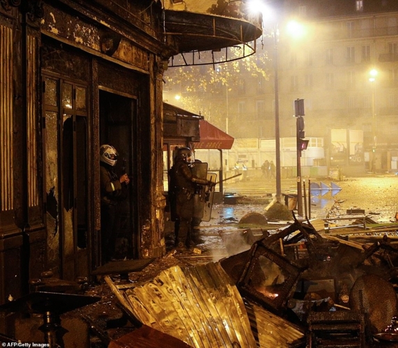Cảnh sát chống bạo động đứng giữa đống đổ nát của một nhà hàng bị đám đông quá khích đập phá. Ảnh: AFP/Getty.