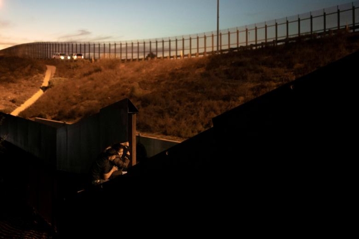 Người nhập cư đang cố trèo qua một điểm trên hàng rào biên giới Mexico-Mỹ.