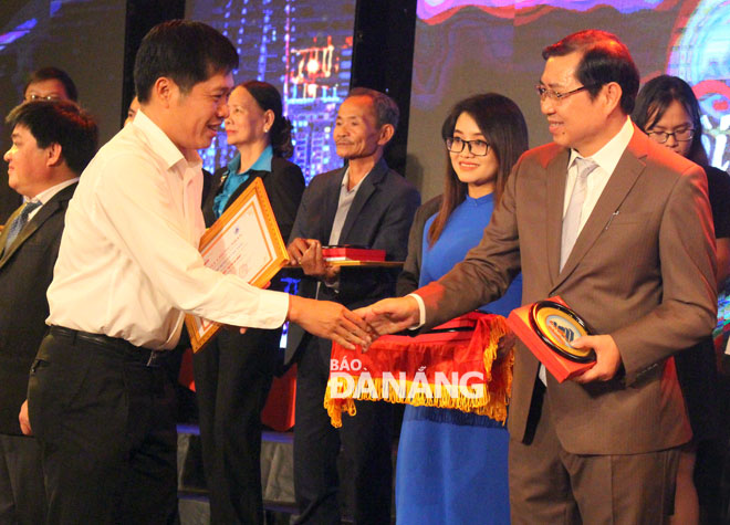 Chủ tịch UBND thành phố Huỳnh Đức Thơ (phải) trao biểu trưng thành phố Đà Nẵng cho các tập thể và cá nhân. 