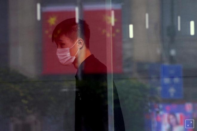 Hình ảnh một người bịt khẩu trang bên trong một cửa hàng ở đường Nam Kinh (Thượng Hải) trước tình trạng dịch viêm phổi cấp đang bùng phát dữ dội ở Trung Quốc. Vì thế, các hoạt động bóng đá của nước này cũng tạm đình hoãn vô thời hạn.  Ảnh: ALY SONG