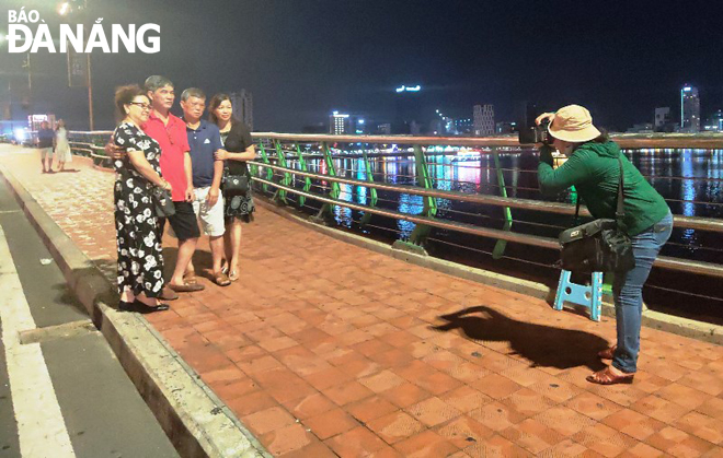 Chị Đoàn Thị Thơ chụp ảnh cho khách trên cầu Rồng. Ảnh: VĂN HOÀNG