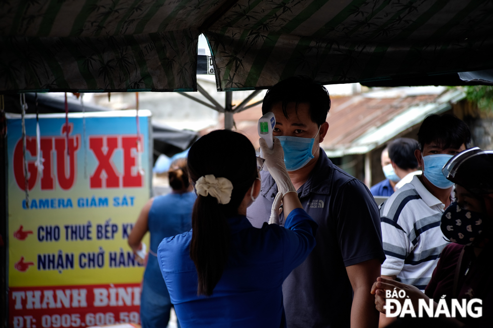 Youth Union members from the Hoa Nhon Commune Youth Union organsiation measuring market-goers’ body temperatures in the Cau Giang Market