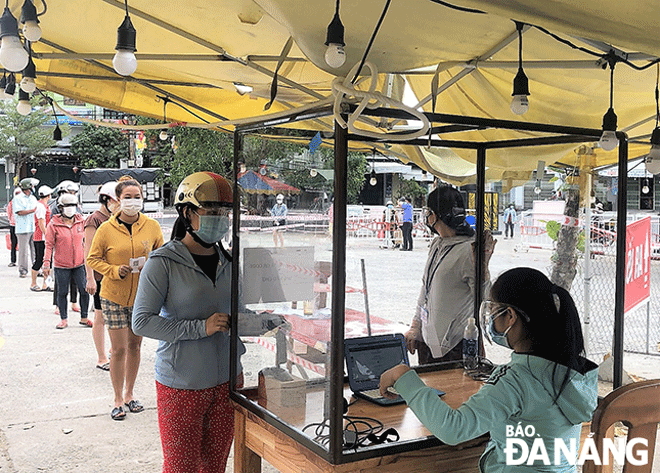 Người đi chợ Túy Loan giữ khoảng cách trong lúc chờ cán bộ kiểm tra mã QR code ở phiếu đi chợ. Ảnh: Ban quản lý các chợ huyện Hòa Vang cung cấp.