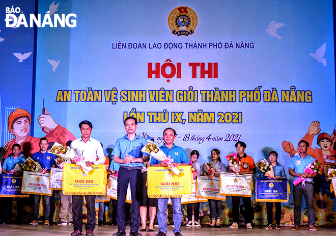 Ông Nguyễn Duy Minh (đứng giữa) trao phần thưởng cho 2 tập thể giành giải nhì Hội thi An toàn vệ sinh viên giỏi thành phố Đà Nẵng lần thứ IX, năm 2021. Ảnh: TIỂU YẾN