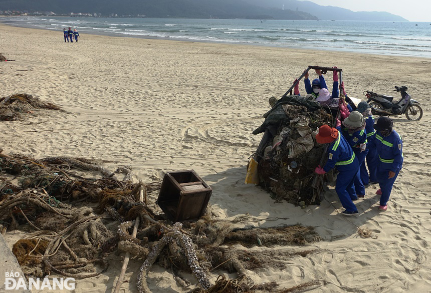 Các công nhân rất vất vả thu gom, di chuyển các loại rác tấp vào bãi biển lên bờ để dễ đưa lên xe chở đến bãi rác Khánh Sơn.
