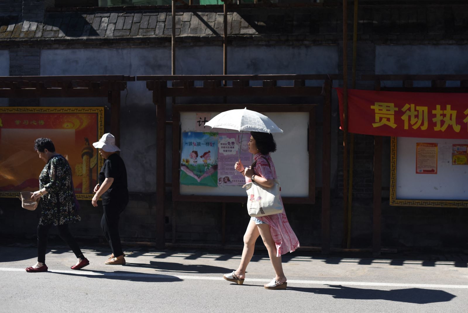  Người dân dùng ô che nắng ở Bắc Kinh, Trung Quốc. Ảnh: AFP/TTXVN