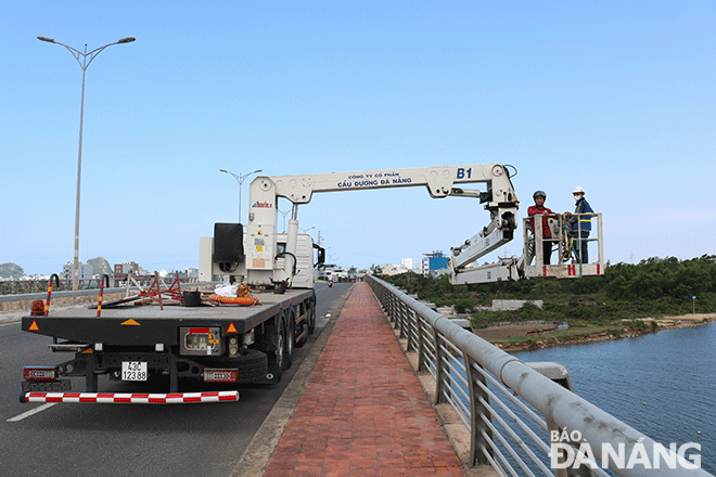 Xe chuyên dụng của Công ty CP Cầu đường Đà Nẵng hỗ trợ đưa cán bộ kỹ thuật, tuần tra xuống kiểm tra vị trí dầm cầu tại cầu Khuê Đông, phường Hòa Xuân, quận Cẩm Lệ. Ảnh: TIỂU YẾN