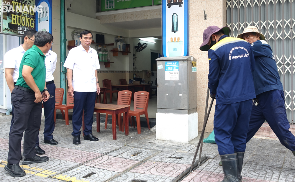 Chủ tịch UBND thành phố Lê Trung Chinh (thứ 3 từ phải sang) chỉ đạo tháo dỡ một hố ga trên vỉa hè đường Lê Duẩn và yêu cầu đơn vị chức năng khắc phục bất cập của hệ thống thoát nước. Ảnh: HOÀNG HIỆP