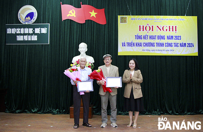 Chủ tịch Hội Văn nghệ dân gian thành phố Đinh Thị Trang (bên phải) tặng hoa và giấy khen cho các tác giải đạt giải thưởng năm 2023. Ảnh: X.D