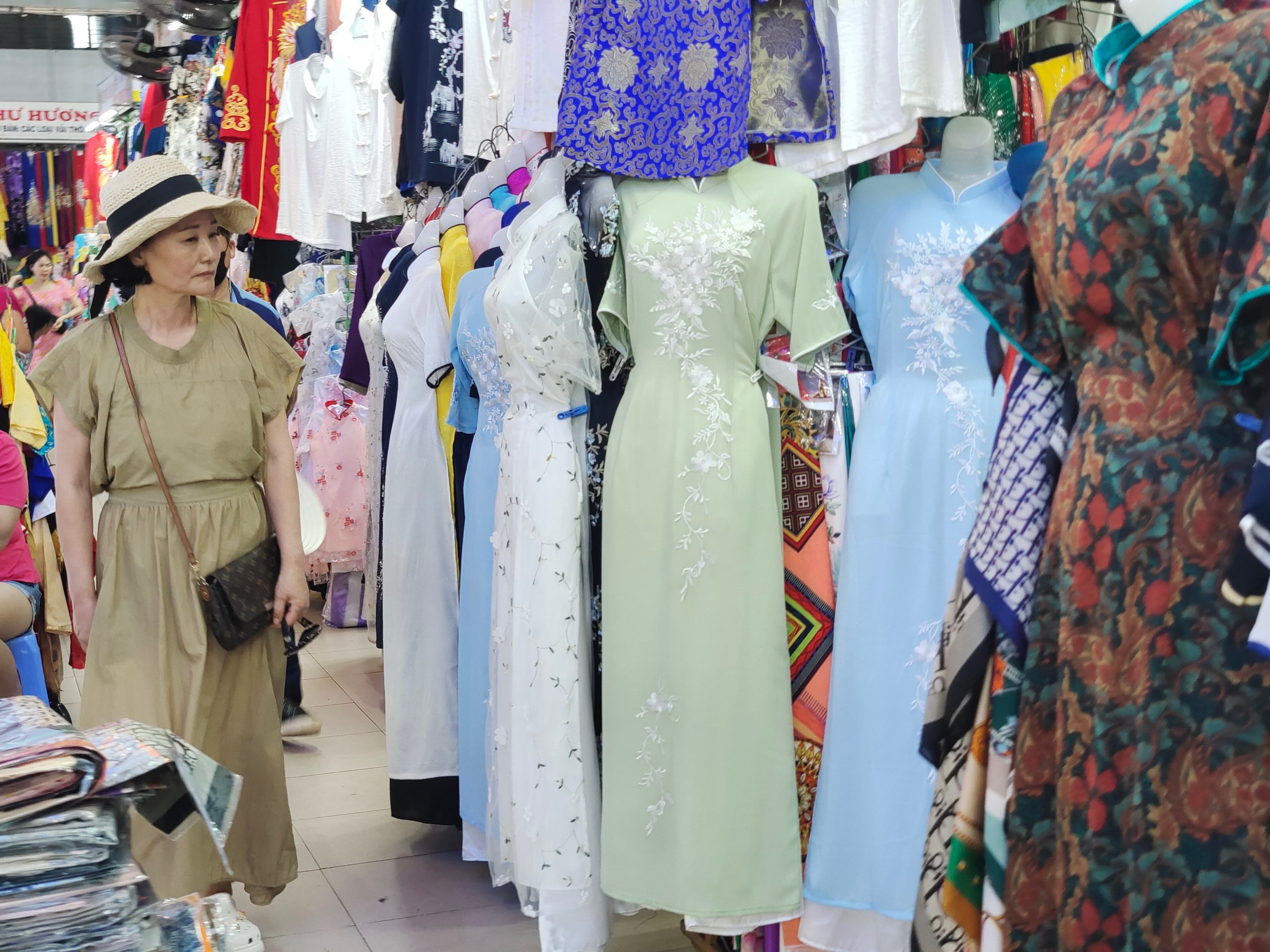 A foreign tourist visiting the Han Market is quite interested in the Vietnamese ‘ao dai’ designs on display for sale and rent. Photo: DIEP NHU