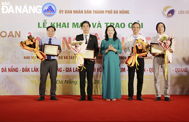 Chủ tịch Hội Nghệ sĩ nhiếp ảnh Việt Nam Trần Thị Thu Đông trao kỷ niệm chương vì sự nghiệp nhiếp ảnh cho Phó Chủ tịch UBND thành phố Trần Chí Cường (thứ 2, bên trái qua) và các đại biểu. Ảnh: X.D