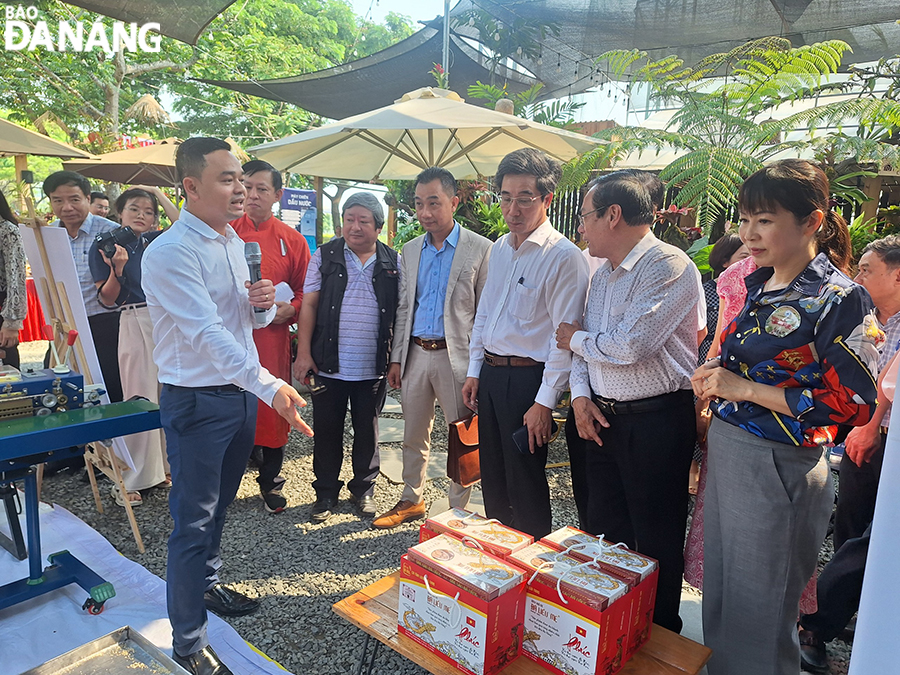 Da Nang People's Committee Vice Chairman Tran Chi Cuong (3rd, right) visits the dried sesame seed cakes booth at the event. Photo: THU HA
