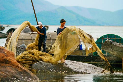   Two fishermen washing a fishing net