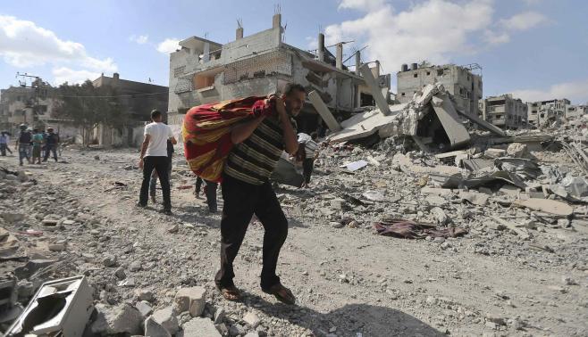 Một người dân Palestin ra đi với những gì còn sót lại từ căn nhà bị đổ nát từ các cuộc oanh kích của Israel trên Dải Gaza, ngày 26-7-2014. Ảnh: Reuters 