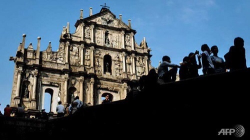 Du khách ngồi trước Di tích Thánh đường Thánh Paul tại Macau - Ảnh: AFP