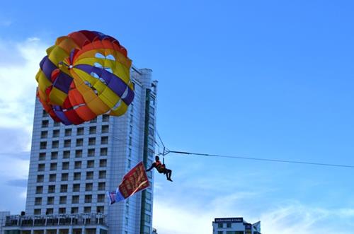 An athlete carrying a banner to celebrate National Day during his parasailing demonstration.