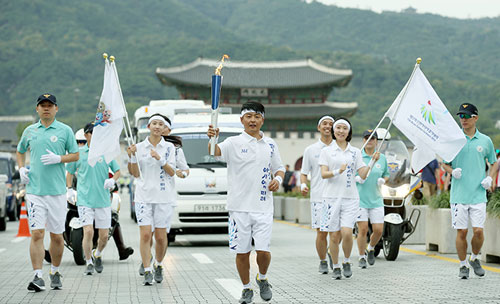 One of the torch bearers runs along Sejongdae-ro with Gwanghwamun as a backdrop, in Seoul on September 16. (Photo: Korea.net)