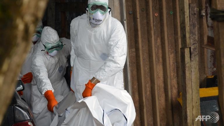 Các nhân viên Chữ Thập Đỏ Liberia mang bảo hộ lao động để đưa thi thể nạn nhân Ebola ra khỏi một nhà xe tại một quận ở thủ đô Monrovia, ngày 19-9-2014. Ảnh: AFP