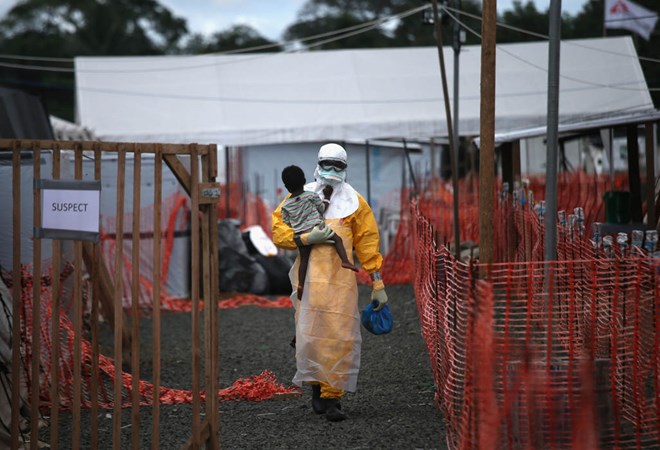 Một nhân viên y tế bế bé trai nhiễm Ebola đi vào trung tâm điều tị tại Liberia (Nguồn: AP)