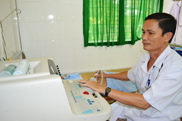 Trạm y tế Hòa Phong có bác sĩ và máy móc tương đối bảo đảm khám ban đầu. Trong ảnh: Bác sĩ CK I Nguyễn Triêm siêu âm bụng cho bệnh nhân. 