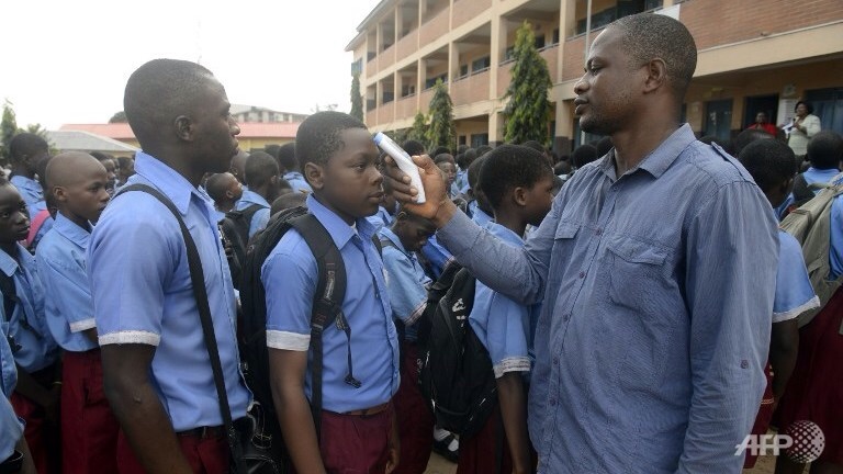 Một giáo viên đang kiểm tra nhiệt độ của học sinh để xem có virus Ebola hay không tại một trường học ở Lagos.  Ảnh: AFP