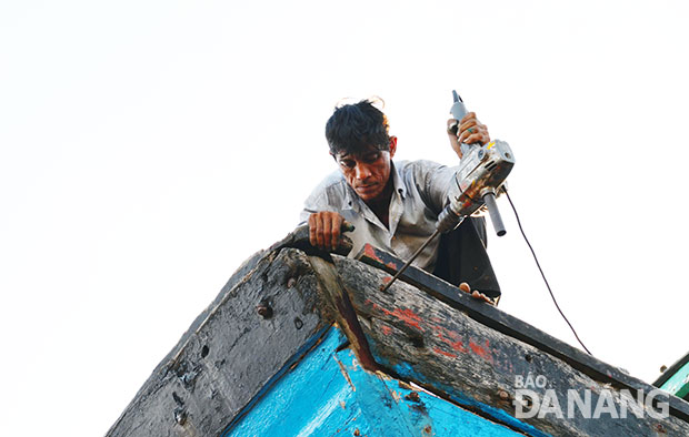 Thợ cả Trần Sinh đang gia cố một chiếc tàu cũ.