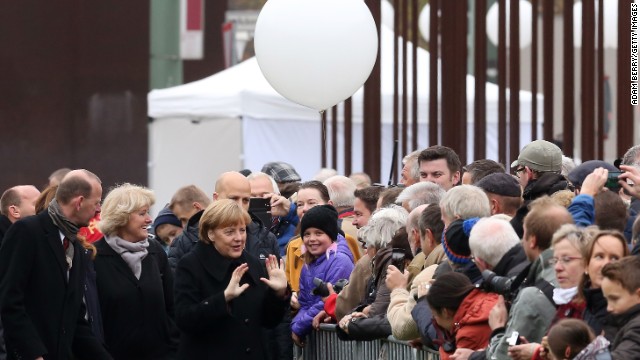 Thủ tướng Merkel và các quan chức chào đón quan khách khi họ đi tới dự lễ Hàn gắn phía sau một mảng Tường Berlin. 