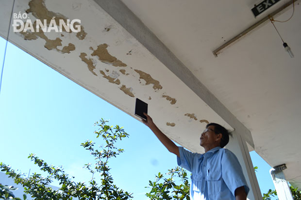 Ông Lê Minh Đệ chỉ vết bong tróc trần hành lang tầng 3, khu chung cư Thuận Phước khiến người dân lo lắng.