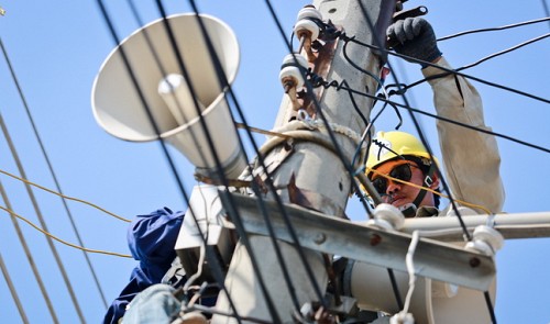 Workers fix power lines on a power pole in Khanh Hoa Province on April 5, 2014.