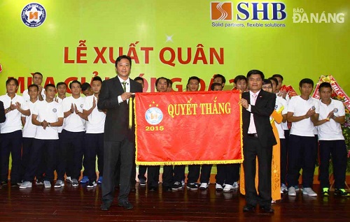 The Director of the municipal Department of Culture, Sports and Tourism (right) presenting a flag for good luck to SHB DN’s coach Le Huynh Duc