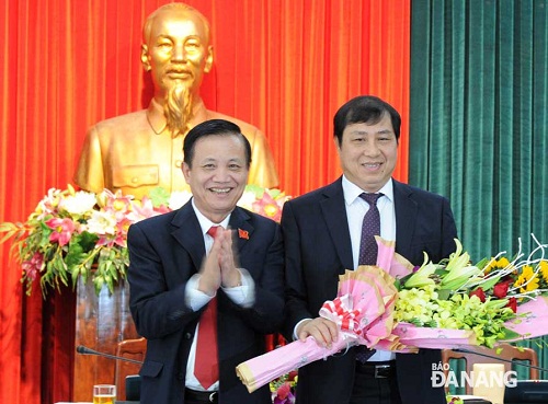 Municipal Party Committee Secretary Tran Tho (left) presenting flowers to Mr Huynh Duc Tho