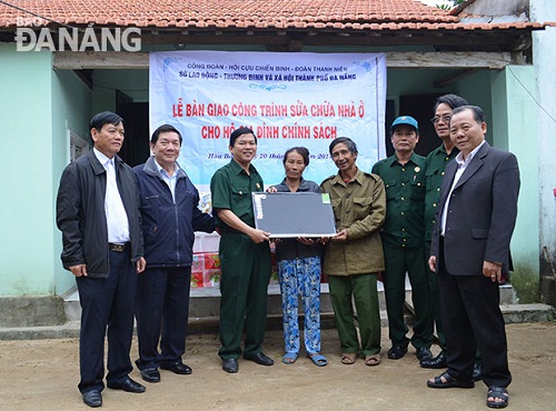 A local social policy beneficiary (4th left) in front of her repaired home