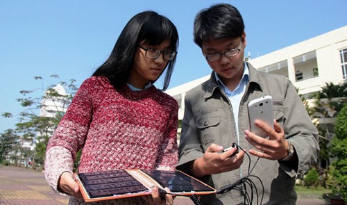 Doan Tran Vien (R) and Nguyen Thuy Tien, two 11th grade Vietnamese students, are seen trying out their solar cellphone charger. Tuoi Tre