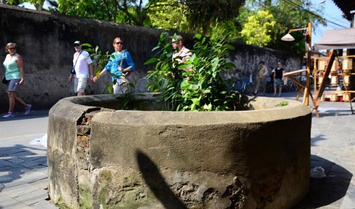 Foreign tourists are seen walking near a dilapidated ancient well in Hoi An City