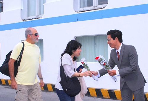 A leader from the Department of Culture, Sports and Tourism presenting flowers to the first cruise ship passengers to set foot in the city in the new year.